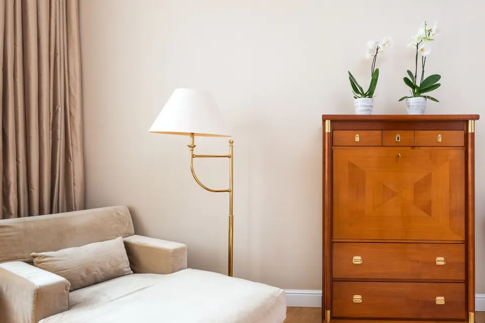 Een rustige kamer met een bank, een lamp en een houten kast